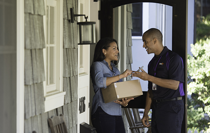 FedEx courier handing a package to a smiling customer