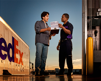 Worker in a warehouse applying a FedEx label to a box