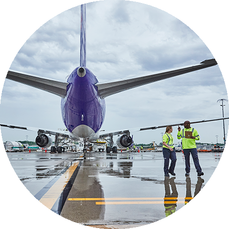 FedEx workers behind a plane on a runway