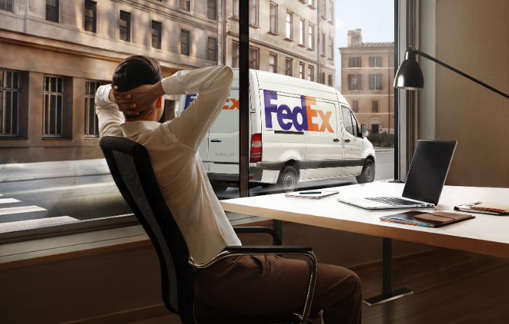 Mann lehnt sich im Stuhl zurück, im Hintergrund ein FedEx Lieferwagen auf der Straße