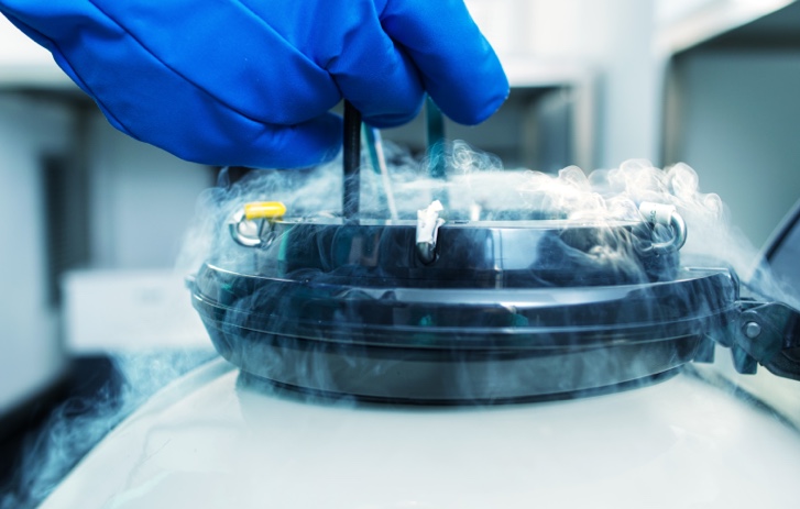 Person wearing gloving above a dry ice container