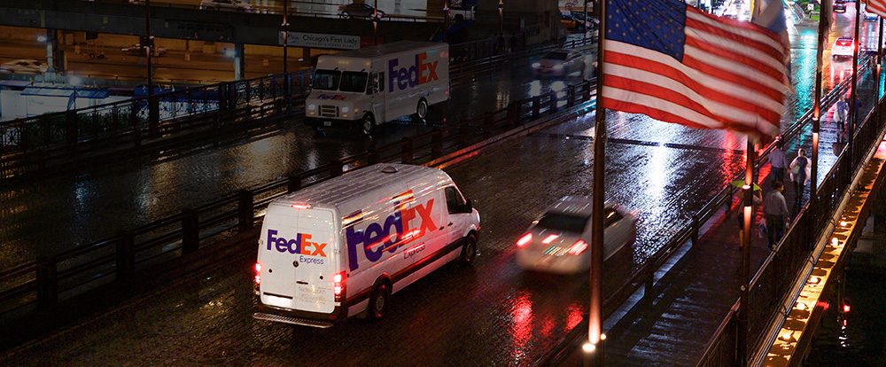 FedEx van and other cars on wet street at night