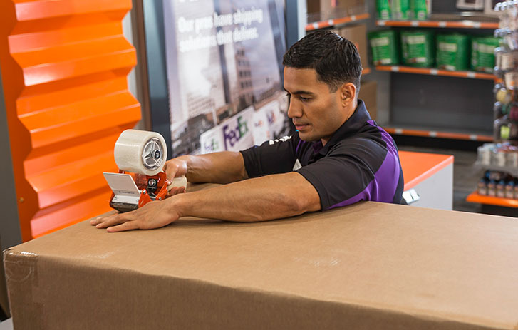 FedEx associate packing a box with packing tape