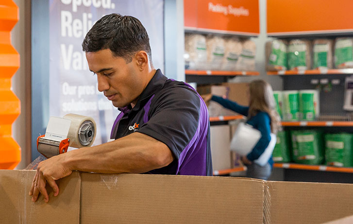 Associate taping a box with a packing tape device