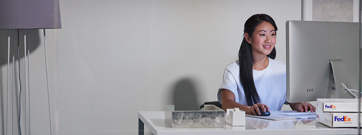 A young woman smiles happily as she works on her computer