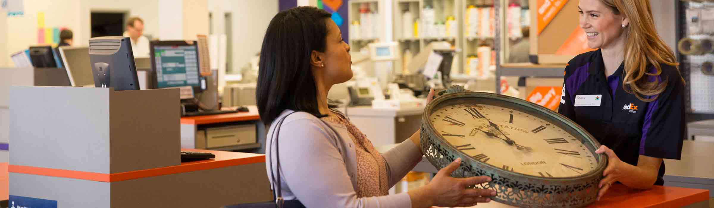 Image of a customer handing over a clock to a FedEx Office team member to be packed and shipped.