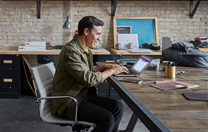 A man works on a laptop in his home office.