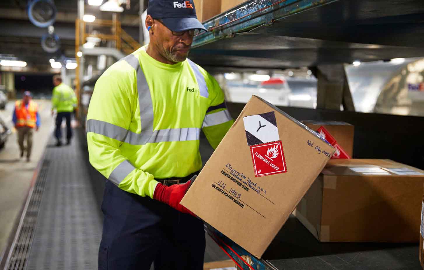 A FedEx team member holding a package with labels on it.