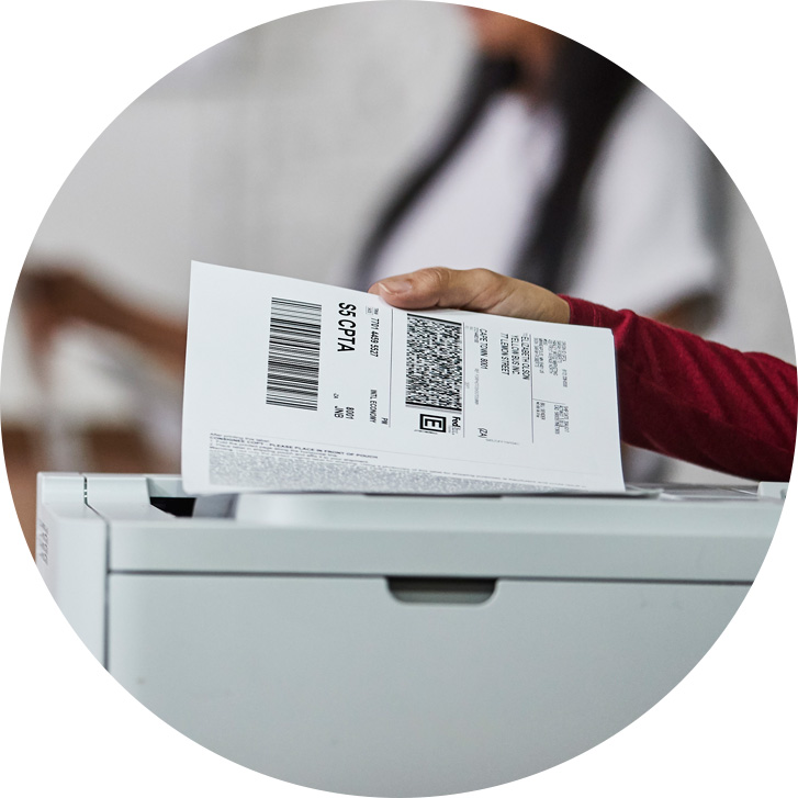 Hand holding shipping label above printer