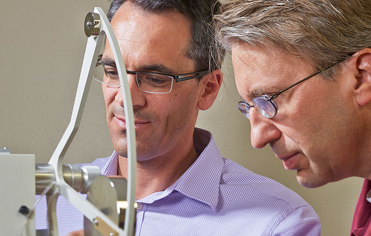 Two male FedEx employees using a tool to test packaging in the FedEx Packaging Lab.