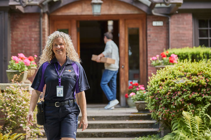 courier walking happily away from residence with customer in the background